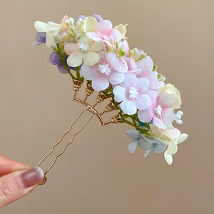 Close-up of a handmade floral hair fork with colorful cloth petals and gold prongs
