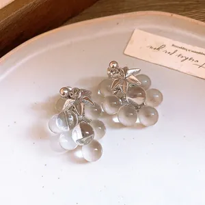 Detailed macro shot of clear crystal grape cluster earrings featuring a silver leaf design.