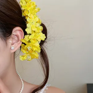 Close-up of a yellow fabric flower hairpin styled in a bun for a fresh, elegant look.