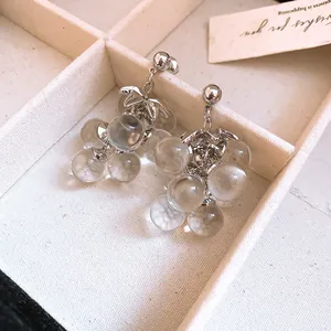 Detailed close-up view of silver needle crystal grape cluster earrings in a white tray