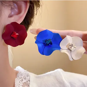 Detail of matte painted flower earrings with central square rhinestones in various colors.