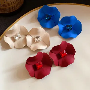 Detailed view of matte painted flower stud earrings with sparkling center square crystals
