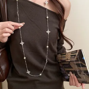 Elegant long chain necklace featuring pearl beads and sparkling rhinestone cross charms.