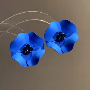 Detailed macro view of blue painted flower earrings featuring a dark square crystal center.