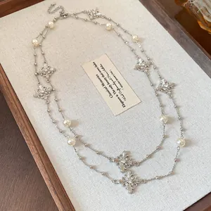 Detailed view of a double-layered silver necklace with pearls and rhinestone crosses.