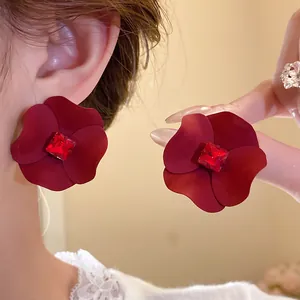 Detailed macro view of matte red flower earrings with sparkling ruby center