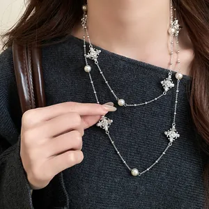 Detail view of elegant silver-tone beaded cross necklace with pearls worn by a model.