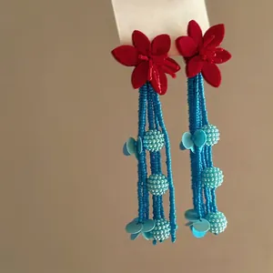 Eleganti orecchini a fiore rosso con lunghe nappe di perline blu in stile vacanziero