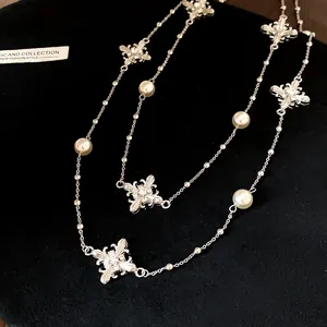 Close-up detail of silver-toned necklace with rhinestones, pearls, and floral charms.