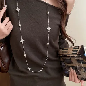 Elegant lifestyle detail of silver pearl cross necklace worn on a brown sweater.