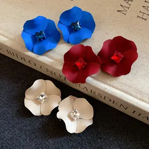 Detail view of matte spray-painted floral earrings with sparkling rhinestone centers.