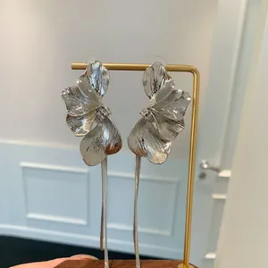 Primo piano di orecchini a petalo di fiore color argento con lunghe nappe