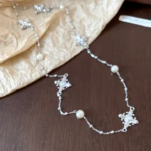 Detailed close-up of a silver-tone necklace featuring pearls and rhinestone cross charms