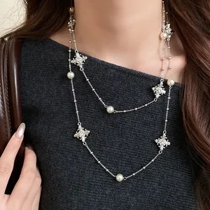 Close-up detail of elegant pearl necklace with rhinestone cross charms on model
