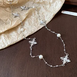 Detailed view of rhinestone cross and pearl beaded necklace on rustic paper background
