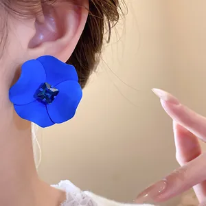 Close-up of matte blue spray-painted flower earring with central blue rhinestone