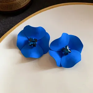 Detailed macro view of matte blue flower stud earrings with dark blue square crystal
