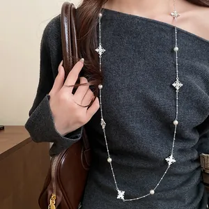 Elegant long necklace featuring pearls and crystal-encrusted cross pendants on model.