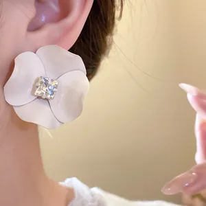 Detailed view of white painted flower stud earring featuring a square center crystal