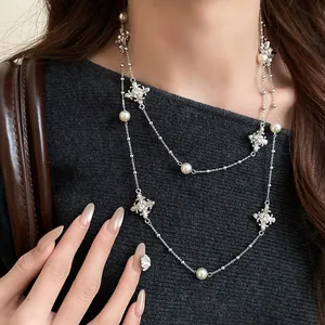 Close-up of elegant double-layered silver cross necklace with pearls and diamonds.