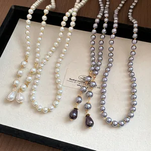 Detail view of vintage long pearl necklaces in cream and grey with teardrop pendants