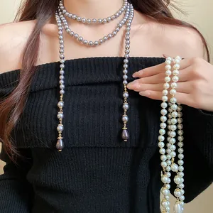Detail showing an elegant multi-layer long pearl necklace with a teardrop pendant