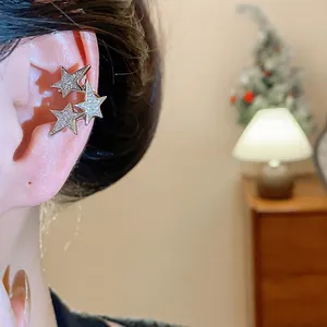 Vista macro di un earcuff a stella in argento con zirconi indossato sulla cartilagine