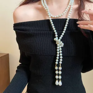 Detail of long multi-layer vintage pearl necklace on model with black off-shoulder top