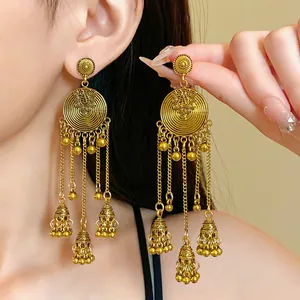 Close-up of vintage ethnic gold tassel earrings with intricate round filigree and bell charms.