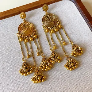 Close-up of vintage ethnic gold-colored tassel earrings with intricate circular patterns.
