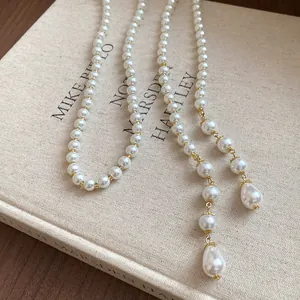 Vintage long pearl lariat necklace with gold-tone accents on a book background