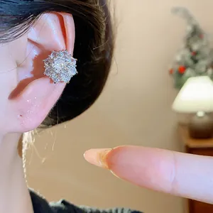 Vista dettagliata di un earcuff a fiore con zirconi scintillanti indossato sull'orecchio.
