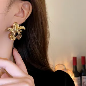 Close-up macro view of vintage irregular gold flower stud earring worn on a model's ear