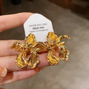 Close-up detail showing the intricate textured petals of these golden flower earrings