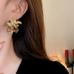 Detailed close-up view of vintage gold irregular flower stud earrings worn by a model
