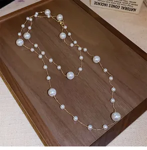Detailed view of French vintage layered necklace with irregular pearls on a wooden tray