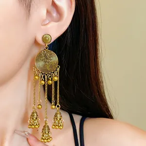 Close-up view of vintage ethnic golden tassel earrings with round floral pattern on model