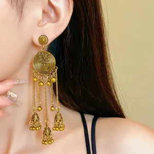 Vintage ethnic gold tassel earrings featuring intricate round floral design on model