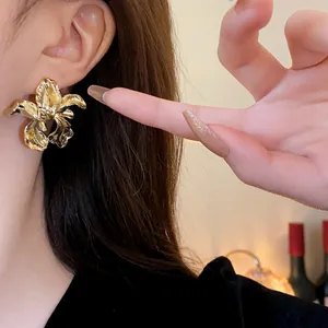 Close-up view of elegant irregular gold iris flower stud earrings worn on a model's ear