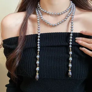 Detail view of a vintage long grey pearl necklace with gold spacers on a model