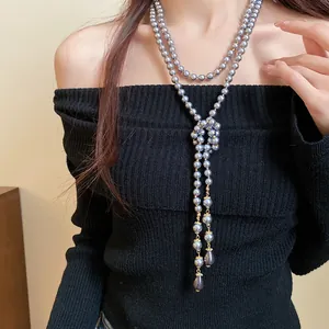Detailed close-up of a vintage long layered charcoal pearl necklace on a model.