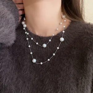 Elegant double-layered pearl necklace with irregular pearls worn on a dark fuzzy sweater.