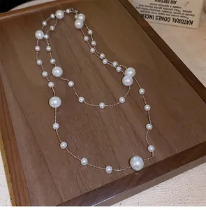Detailed close-up of double-layer irregular pearl necklace on a vintage wooden tray