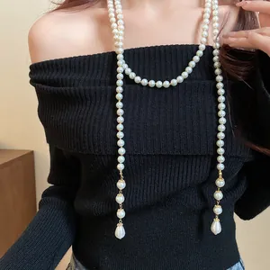 Elegant vintage multi-layer pearl necklace featuring a teardrop pendant worn on a black sweater