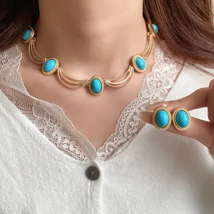 Close-up of vintage palace style oval turquoise necklace and earring set on model