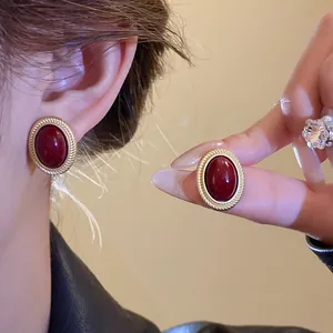 Detail view of high-quality vintage oval burgundy gemstone earrings with gold rope border