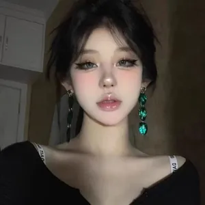 Close-up of model wearing emerald green tiered drop earrings in French vintage style