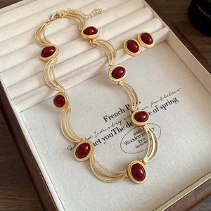 Close-up of vintage gold-tone necklace and earrings set featuring oval red gemstones