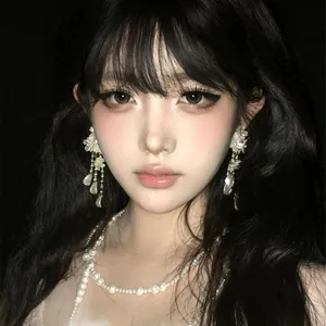 Close-up of elegant white floral tassel earrings with pearl details on an Asian model