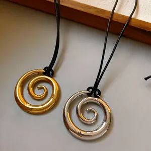 Vista dettagliata di ciondoli a spirale in metallo oro e argento su cordini neri